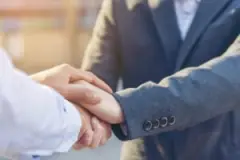 Faceless attorney and clients shake hands.