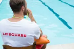 A lifeguard sitting on the side of a pool. A drowning accident attorney in Lafayette can help you seek compensation after a swimming pool accident.