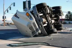 A flipped white truck cab at an intersection.