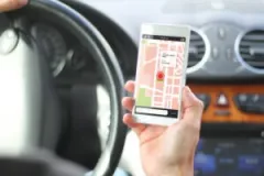A faceless rideshare driver looks at an app with a ride request.