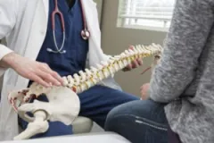 A doctor and patient examine a model of a spine to discuss spinal cord injuries with an Evansville lawyer.