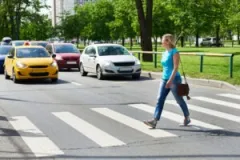 A woman crossing the road. You may work with a Michigan City pedestrian accident lawyer after a collision while out walking.