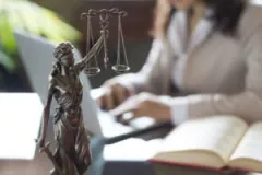 South Bend Amazon truck accident lawyer reads legal books with scales of justice statue on her desk.
