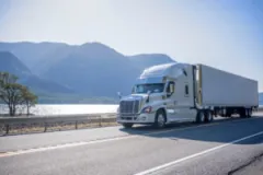 A semi-truck drives down a mountainous highway.