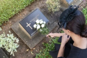 A grieving parent leaves flowers at a child’s grave.