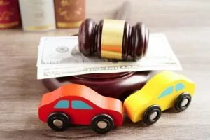 A mock-up of a car accident takes place on a lawyer’s desk as a victim pursues a rideshare accident claim.