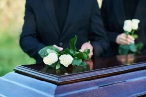 Two people at a funeral. A lawyer can explain how much cases are worth when someone dies in a car accident. 