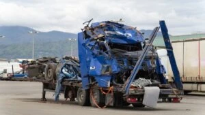 A tow truck hauls a damaged truck away from an accident scene.