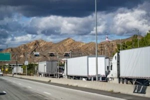 A line of semi trucks approaching a weight station to determine how much they weigh. If they are over, they could be fined.