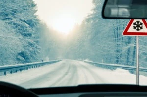 A trucker driving on a snowy road in winter during the holidays. He’s at a higher risk of a trucking accident due to the weather.