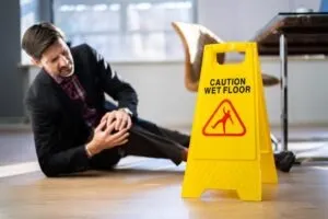 man holding knee by slippery floor sign