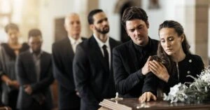 family standing in line at a funeral to say goodbye to a departed loved one