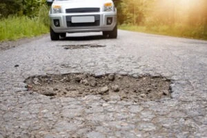 A car approaches a pothole on a Florida road. If you have pothole damage, you can consult a personal injury lawyer on how to get reimbursement.