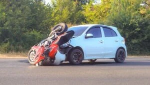 Car and motorcycle in an accident, with the rider of the motorcycle off to the side and wondering who pays their medical bills after a motorcycle accident