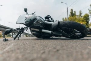 A black motorcycle lays on its side on the road after a motorcycle accident