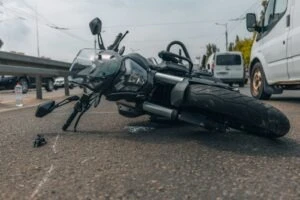 Motorcycle lying on the side of the road after an accident, with the rider of the bike nearby and wondering if they should go to the doctor after a minor motorcycle accident.