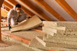 expert installs insulation in attic