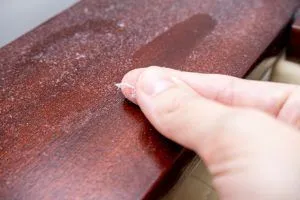 finger wiping layer of dust off wooden surface
