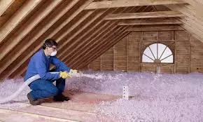 worker installs insulation in attic