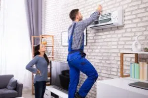 Customer watching repair technician fix air conditioner