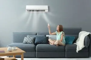 young woman switching on air conditioner