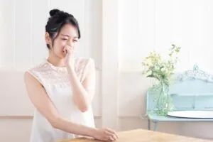 Asian woman holding her nose in the kitchen