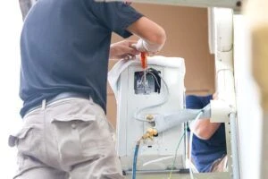 a technician working on a furnace after explaining the best time to get a furnace tune-up.