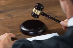 Cropped image of male judge striking the gavel at table