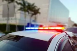 First responder police car cruiser, flashing a full array of blue and red tactical lights against a bokeh roadblock and checkpoint looking for drivers under the influence of liquors or illegal drugs.