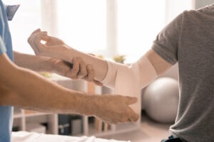 The hands of a clinician are wrapping the arm of a dog bite victim.