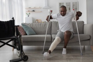a man with a broken leg, cast, and crutches getting up from a couch