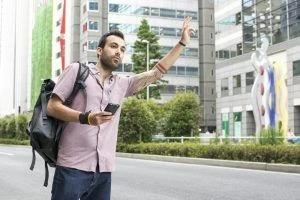 young-white-man-holding-cellphone-hailing-uber-taxi