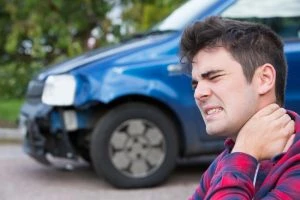 man rubbing his neck after a car accident; whiplash