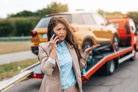 Woman stands near tow truck and calls lawyer to ask them what to do after a hit and run accident.