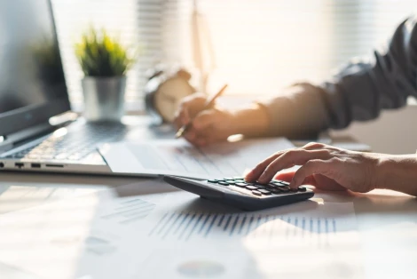 A man uses a calculator as he figures out his tax deduction. If you’re worried about paying taxes on your insurance settlement, consult an attorney.