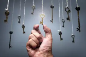 A hand reaching for one gold key amoungst hundreds of normal keys