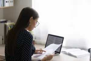 Woman at computer reads nursing license under review letter.