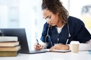 nurse studies with books and coffee nearby