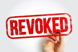 The word “revoked” with a hand holding a marker.