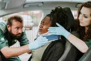 paramedics helping a black female driver with a neck injury