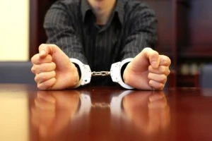 man sitting at a table wearing handcuffs