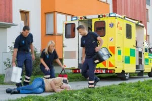 paramedics tending to an elderly man who fell on the sidewalk