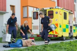 paramedics tending to an elderly man who fell on the sidewalk