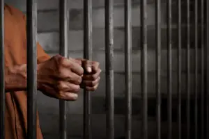 man’s hands holding prison bars