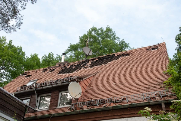 haus mit dachschaden abgedeckten dachziegeln sturm brand feuer unwetter