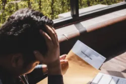 Man resting his head in his left hand while looking down at a piece of paper with “ Termination Letter” written at the top of it and trying to figure out if he can file a claim against his employer in accordance with the Connecticut statute of limitations for wrongful termination.