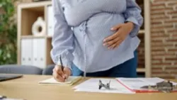 A pregnant employee takes notes at work. A lawyer can advise you on your legal options for proving pregnancy discrimination in the workplace.