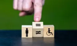 Symbol for equal rights of persons with disabilities. Hand turns a wooden cube and changes the unequal sign to an equal sign.