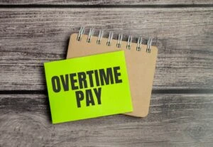 The words "overtime pay" are written on a piece of neon green sticky note paper. If Target has not paid you for the overtime you worked, consult an employment attorney who can file a complaint and take legal action to recover your wages.