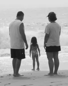 two parents watching their small child at the beach